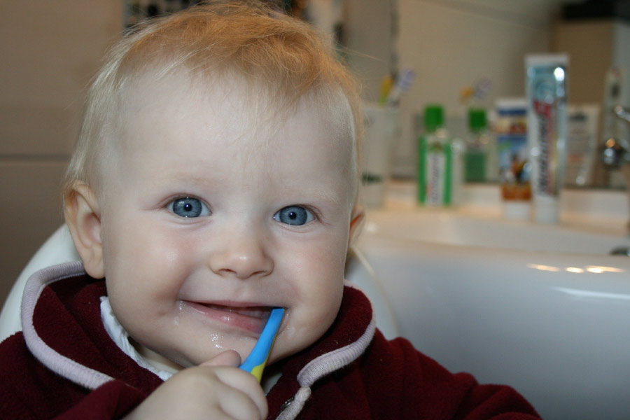 Smiling toddler with a toothbrush in his mouth.